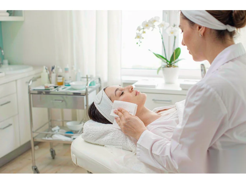 Beauty therapist using a disposable face towel during a facial treatment